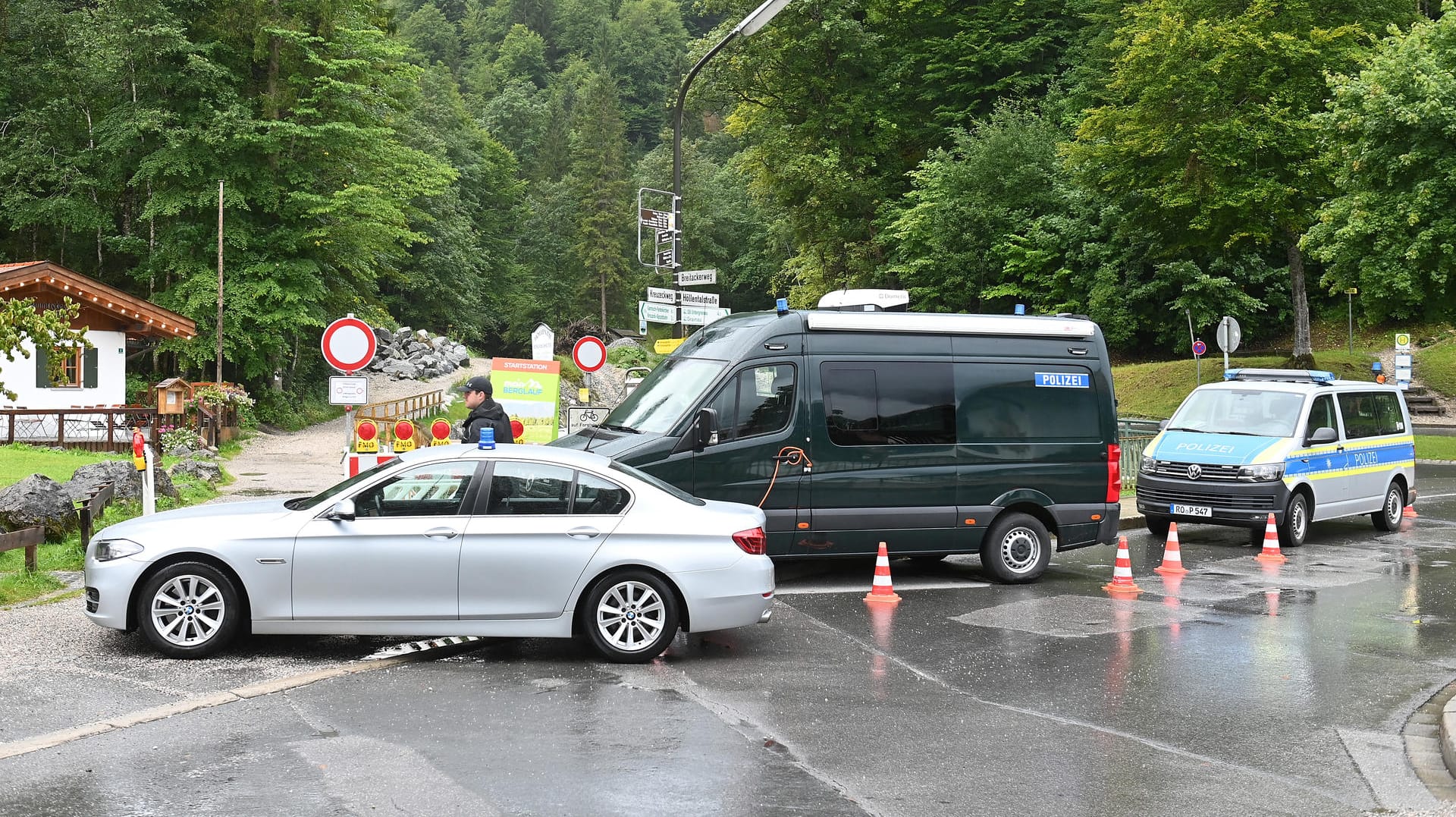 Einsatzfahrzeuge der Polizei stehen am Eingang zur Höllentalklamm: Nachdem eine Frau tot geborgen wurde, geht die Suche nach zwei Vermissten weiter.