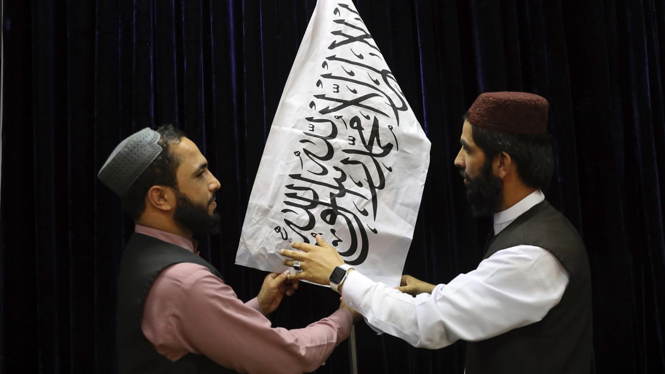 Taliban-Funktionäre hissen ihre Flagge vor einer Pressekonferenz in Kabul.