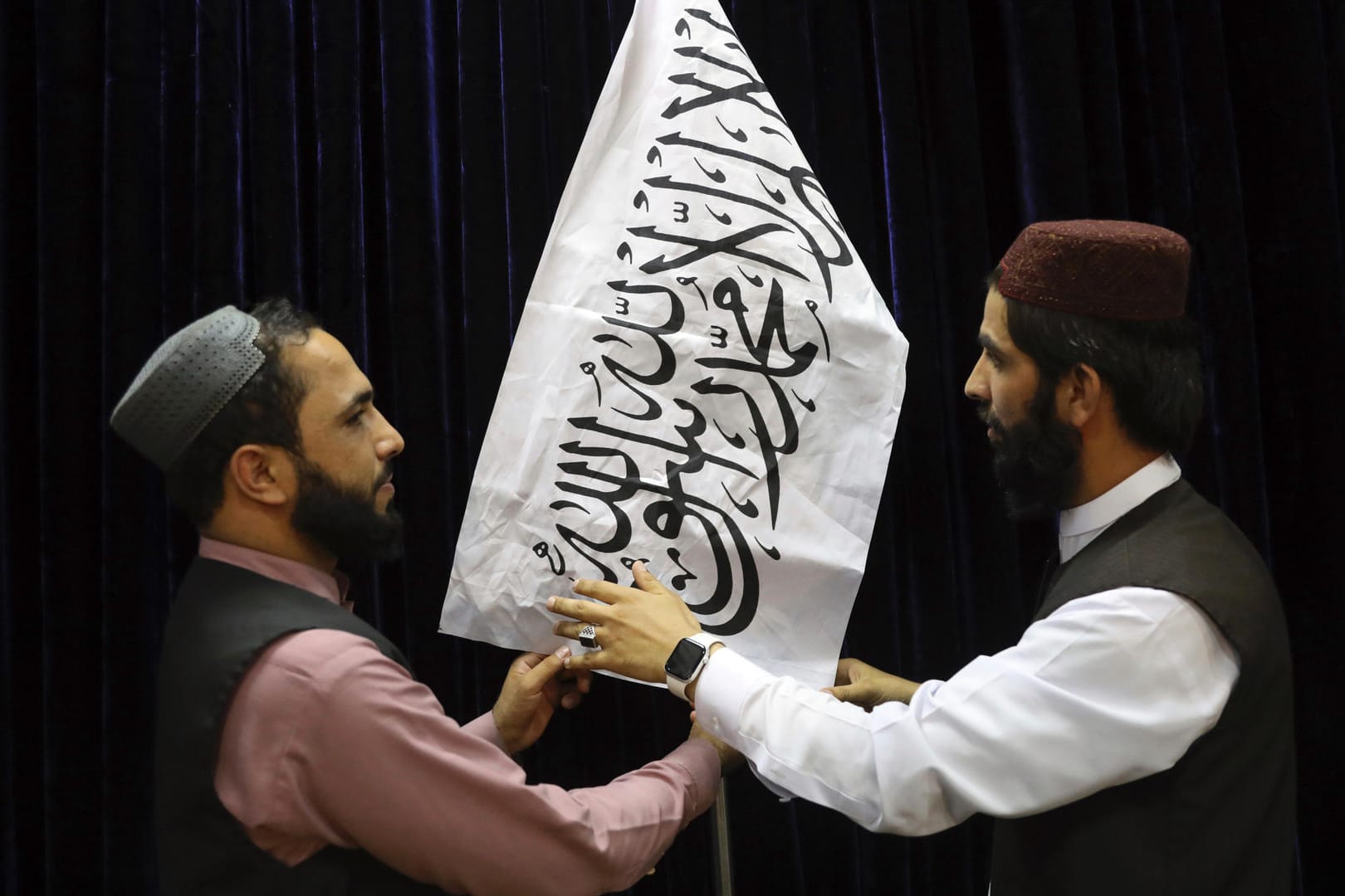 Taliban-Funktionäre hissen ihre Flagge vor einer Pressekonferenz in Kabul.