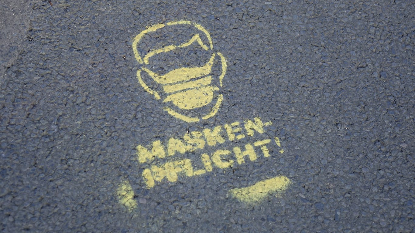 "Maskenpflicht"-Schriftzug auf einem Bürgersteig (Symbolbild): In NRW gelten ab Freitag neue Corona-Regeln.
