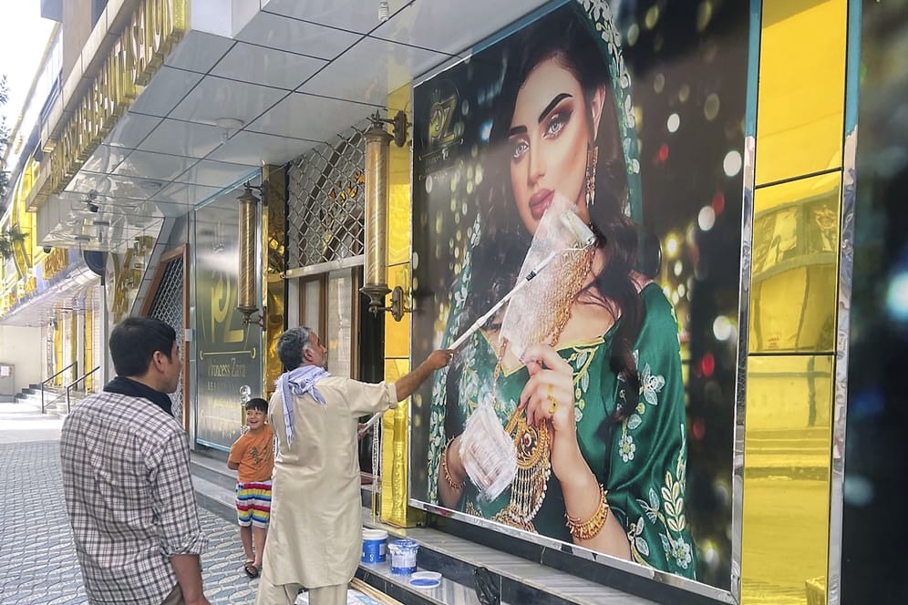 Ein Mitarbeiter eines Schönheitssalons übermalt ein großes Foto einer Frau an der Wand: Die Taliban sind in die afghanische Hauptstadt Kabul eingedrungen.