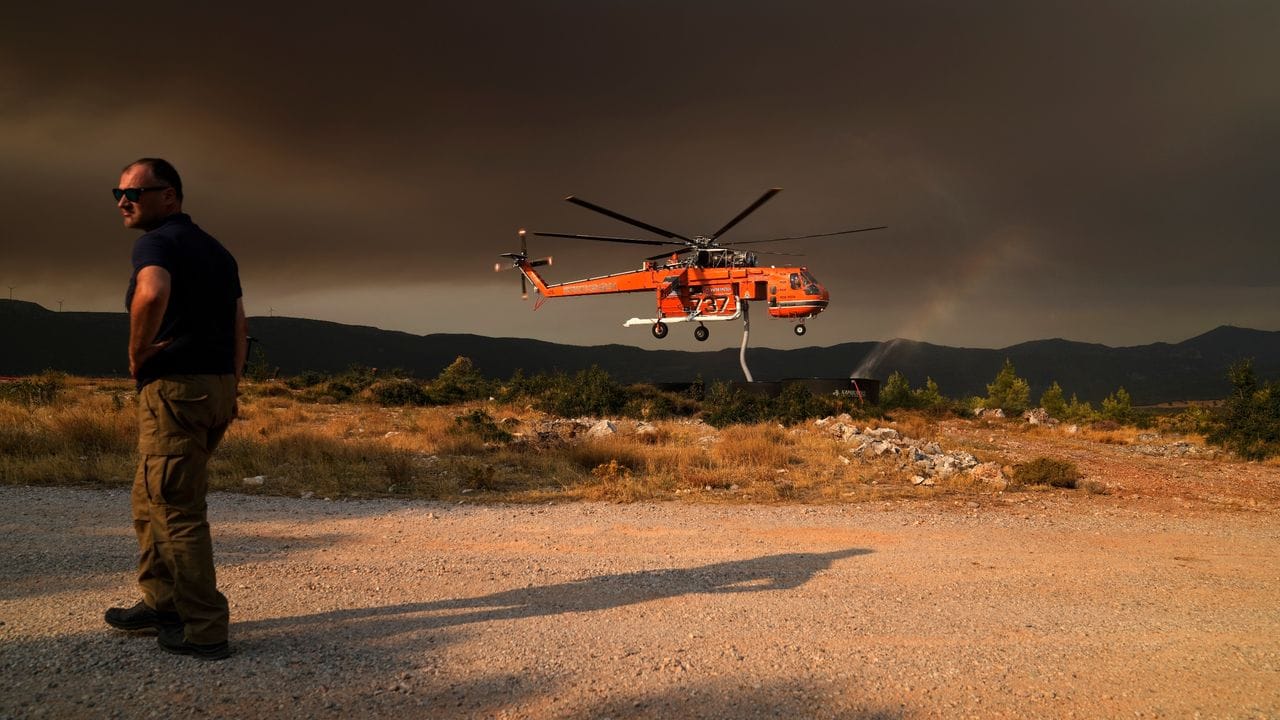 Ein Hubschrauber füllt einen Wassertank, um Vilia vor den Flammen zu schützen.