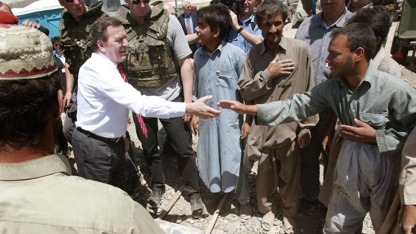 Bundeskanzler Gerhard Schröder begrüßt im Jahr 2002 afghanische Arbeiter im Feldlager der internationalen Afghanistan-Schutztruppe Isaf in Kabul.