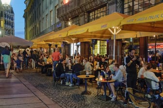 Menschen sitzen in Cafés: Das RKI verzeichnet mehr positive Corona-Fälle.