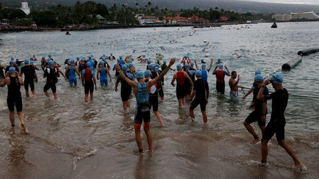 2019: Athleten stehen im Wasser der Kailia Bay für den Schwimmteil des Triathlons. 2019: Athleten stehen im Wasser der Kailia Bay für den Schwimmteil des Triathlons.
