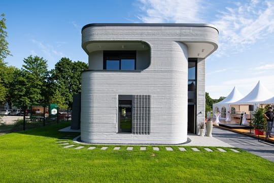 An der Außenfassade des ersten 3D Druckhauses - ein zweigeschossiges Einfamilienhaus - sieht man die mittels eines 3D-Betondrucker aufgetragenen Betonschichten.