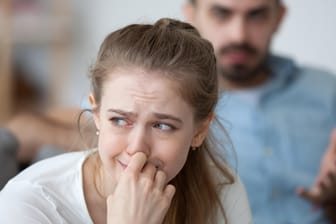 Eine Frau wendet sich weinend von ihrem Partner ab. Alltagsbelastungen und Stress im Job können die Beziehung auf eine harte Probe stellen.