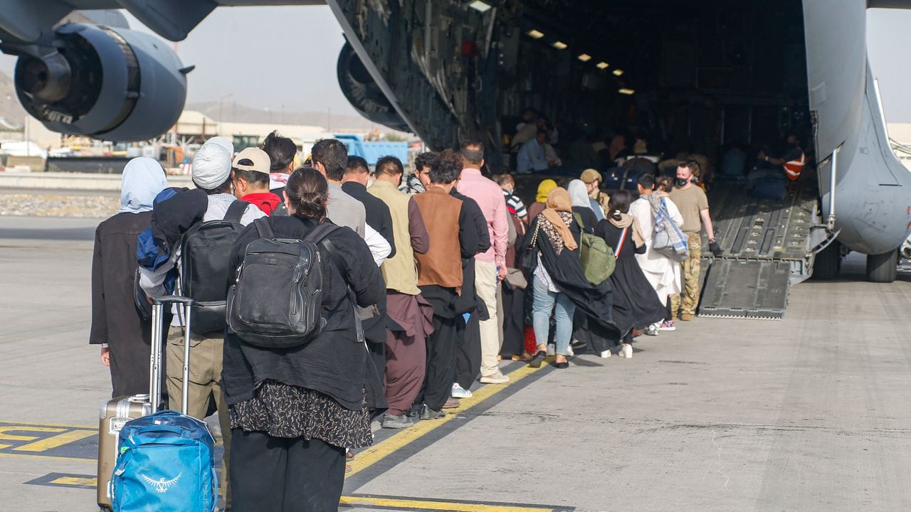 Menschen stehen auf dem Rollfeld und gehen an Bord eines US-Transportflugzeugs von Typ C-17 Globemaster III während ihrer Evakuierung am Hamid Karzai International Airport in Afghanistan. Menschen stehen auf dem Rollfeld und gehen an Bord eines US-Transportflugzeugs von Typ C-17 Globemaster III während ihrer Evakuierung am Hamid Karzai International Airport in Afghanistan.