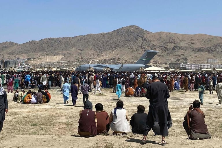 Menschen sitzen am Rollfeld in Kabul: Die Bundeswehr versucht Deutsche und Ortskräfte auszufliegen.