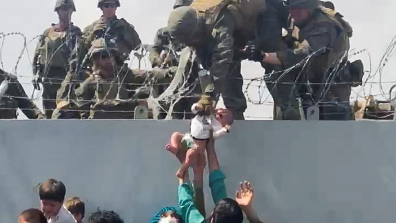 Menschen reichen US-Soldaten ein Baby an der Flughafenmauer in Kabul (Archivbild). Das Kind ist jetzt mit seiner Familie vereint.