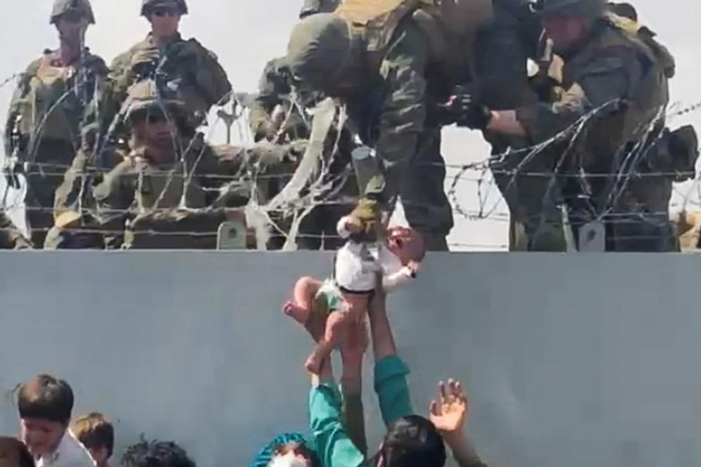 Menschen reichen US-Soldaten ein Baby an der Flughafenmauer in Kabul (Archivbild). Das Kind ist jetzt mit seiner Familie vereint.