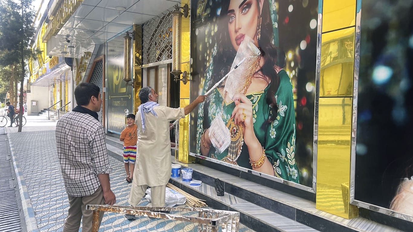 Kabul am 15.08.2021: Ein Mitarbeiter eines Schönheitssalons übermalt ein großes Foto einer Frau an der Wand, nachdem die Taliban in die afghanische Hauptstadt eingedrungen sind. Frauen und Mädchen bangen um ihre Rechte.