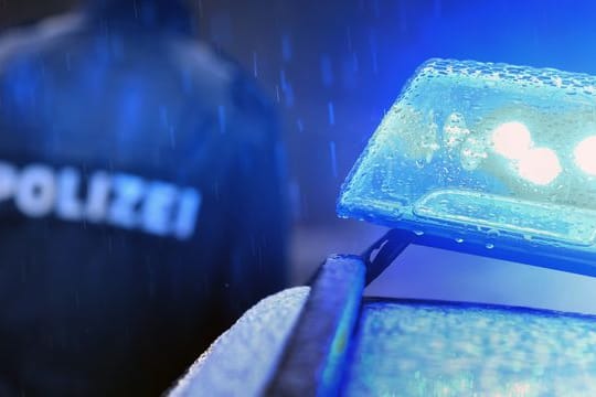 Ein Polizist steht vor einem Streifenwagen mit Blaulicht (Symbolbild): Die Frau des Mannes habe den 32-Jährigen als vermisst gemeldet.