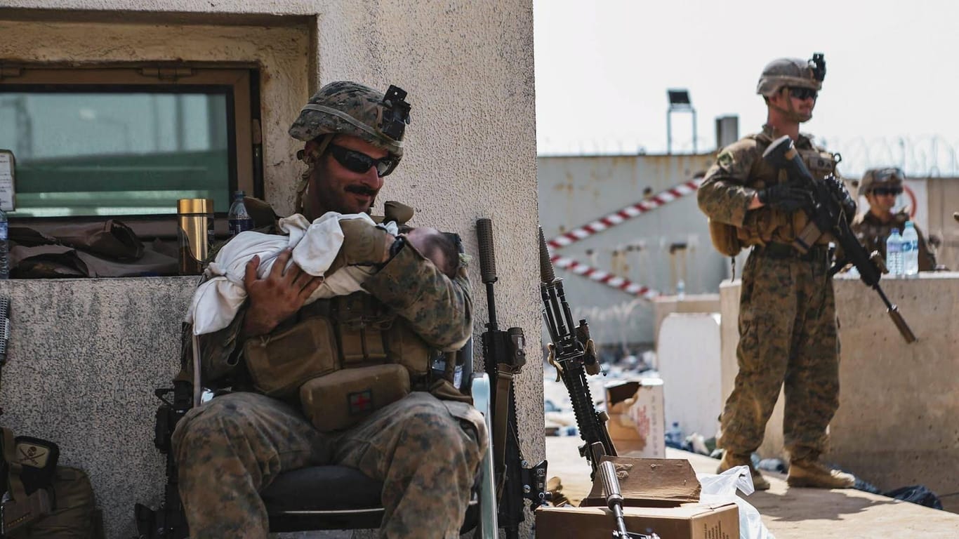 Ein amerikanischer Elitesoldat beruhigt ein Baby auf dem Airport Kabul.