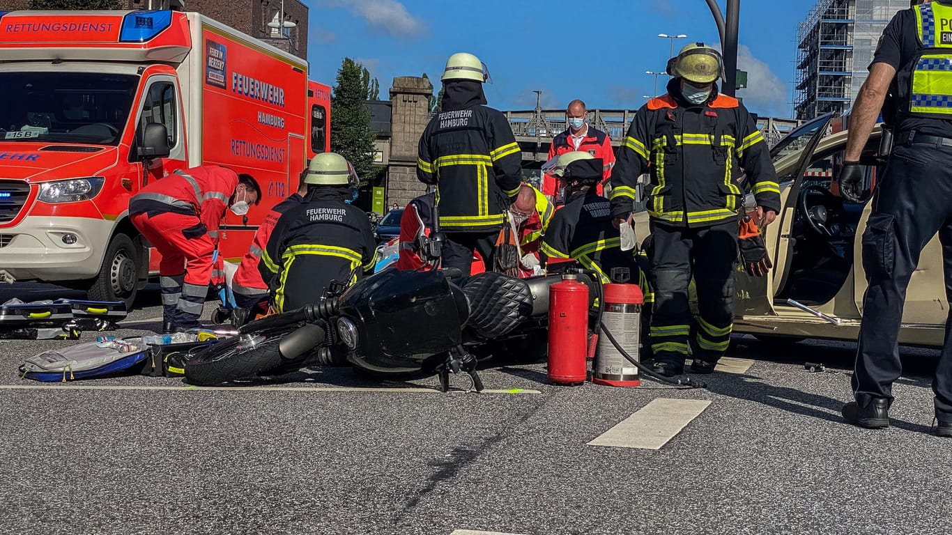 Rettungskräfte der Feuerwehr stehen neben dem Motorrad: Eine Rückenverletzung ist bei dem Motorradfahrer nicht auszuschließen.