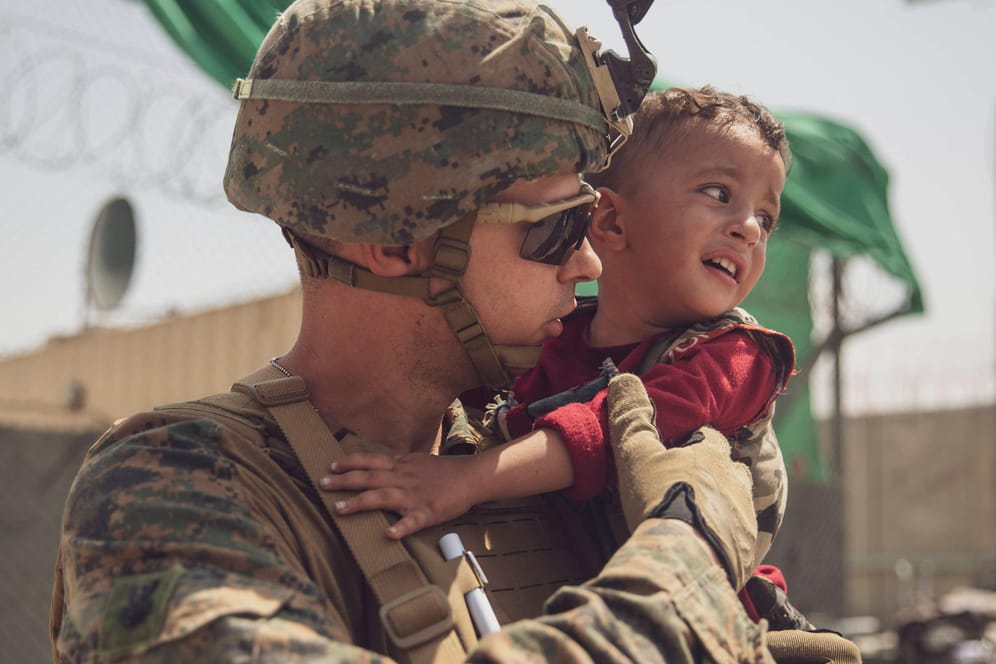 Ein US-Soldat mit einem Kleinkind am Flughafen Kabul: Die Streitkräfte werden wohl Ende August das Land verlassen.