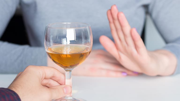 Eine Frau lehnt angebotenen Alkohol ab: Nach dem Entzug sollten alkoholkranke Personen lebenslang abstinent bleiben.