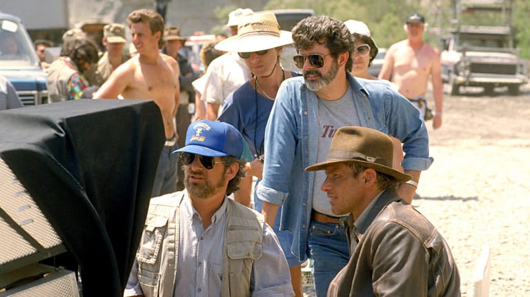 Steven Spielberg (l.u.), George Lucas (blaues Hemd mit Sonnenbrille) und Harrison Ford (r.u.): Das Trio verlieh dem Leinwandhelden Indiana Jones Leben.