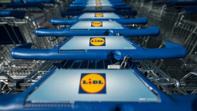 Einkaufswagen stehen vor einer Filiale des Lebensmitteldiscounters Lidl.