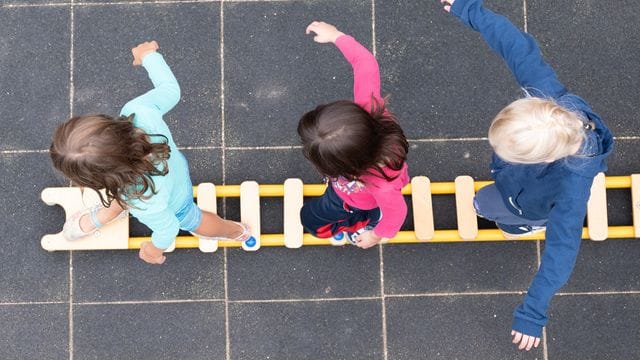 Kinder balancieren auf dem Spielplatz einer Kita Kinder balancieren auf dem Spielplatz einer Kita