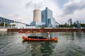 Ein Klimaaktivist paddelt mit seinem Kanu vor dem Kraftwerk