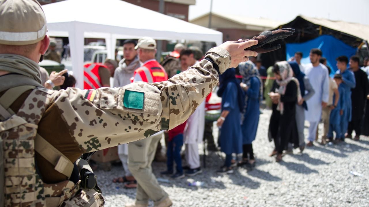 Soldaten und Helfer verteilen Spenden an Menschen, die auf dem Flughafen von Kabul auf eine Ausreisemöglichkeit warten.