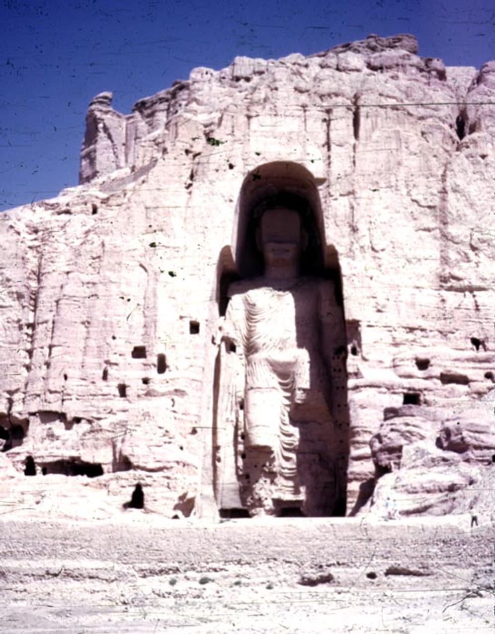 Das Bild zeigt eine der größten stehenden Buddha-Statuen der Welt. Sie war 53 Meter hoch. 2001 wurde sie durch die Taliban zerstört, weil die Scharia ihrer Auslegung zufolge eine Darstellung von menschlichen Figuren verbietet.