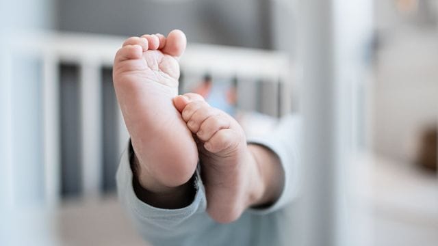 Die Füße eines Babys sind in einem Kinderbett zu sehen