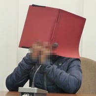 Mann mit einer Mappe vor dem Gesicht: Der Prozess gegen den Angeklagten hat begonnen.