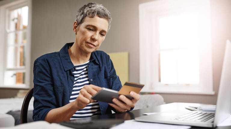 Ältere Frau mit Unterlagen und Smartphone (Symbolbild): Rentenpunkte kaufen, um Abschläge auszugleichen, kann man nach Vollendung des 50. Lebensjahres.