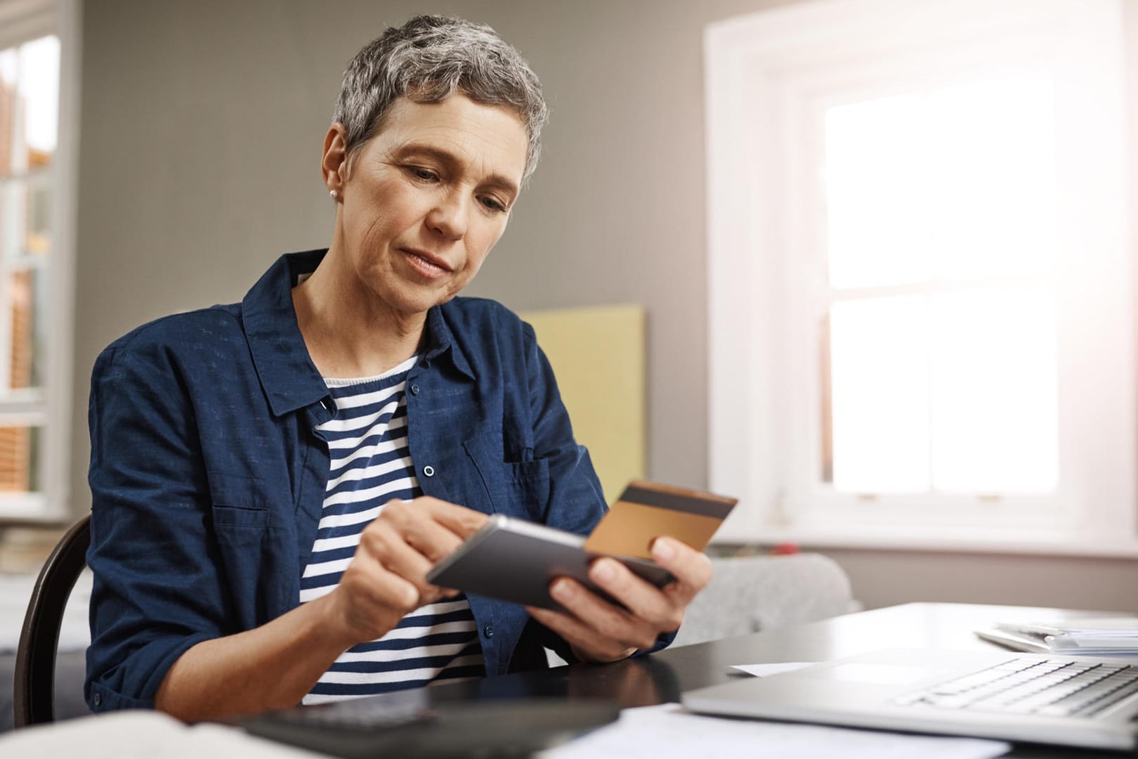 Ältere Frau mit Unterlagen und Smartphone (Symbolbild): Rentenpunkte kaufen, um Abschläge auszugleichen, kann man nach Vollendung des 50. Lebensjahres.