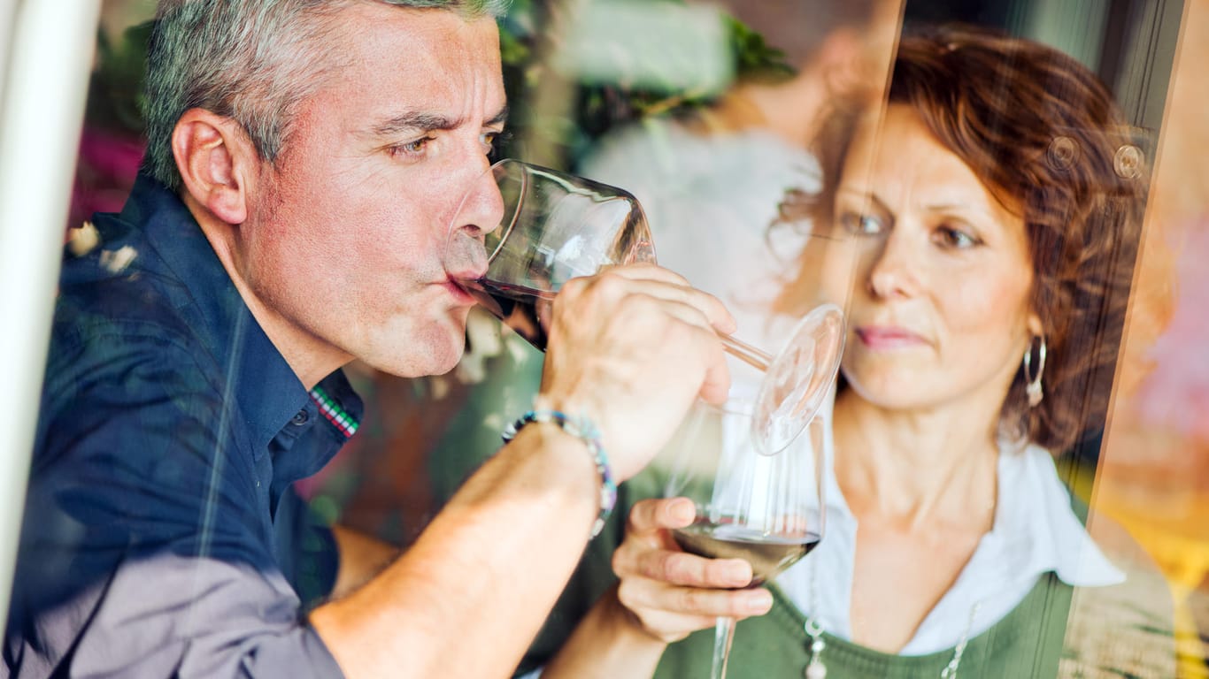 Mann und Frau mit je einem Glas Wein in der Hand: Co-Abhängige fördern das Suchtverhalten des Partners oder der Partnerin.