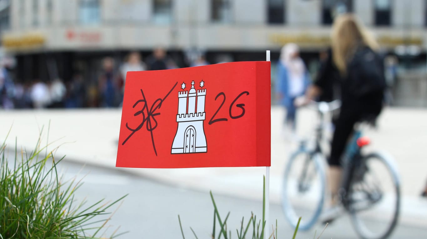 Eine Pappflagge mit dem Hamburg-Wappen sowie der Aufschrift 2G steckt in einem Blumenkübel in der Hamburger Innenstadt: Die Hansestadt führt als erstes Bundesland das sogenannte 2G-Optionsmodell ein.