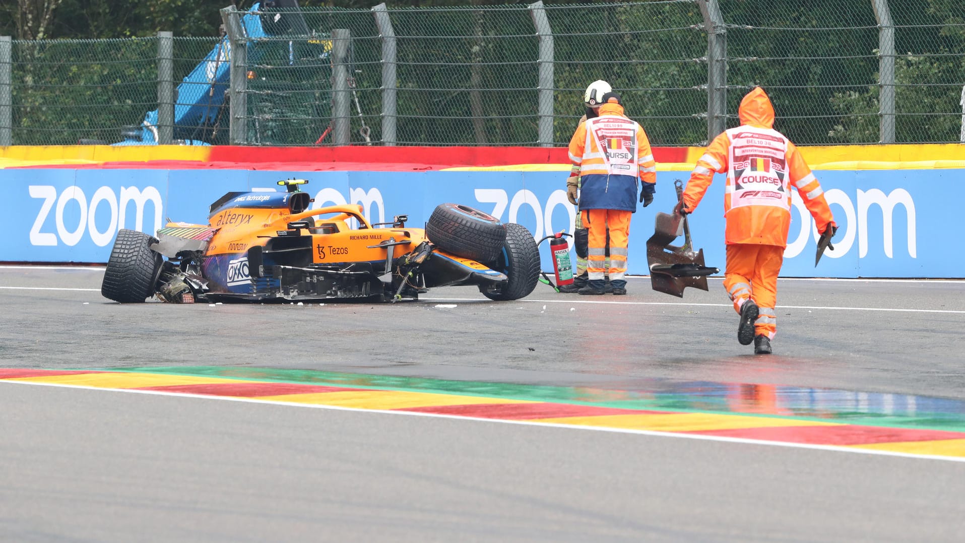 Nach dem Crash Das Wrack von Lando Norris' McLaren steht auf der Strecke, Helfer kümmern sich um die Trümmerteile.