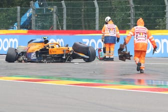 Nach dem Crash Das Wrack von Lando Norris' McLaren steht auf der Strecke, Helfer kümmern sich um die Trümmerteile.