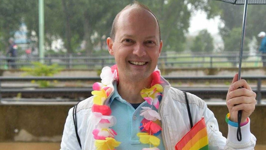 Lukas mit Schirm und Regenbogenfahne: Der 43-Jährige freut sich über die Parade.