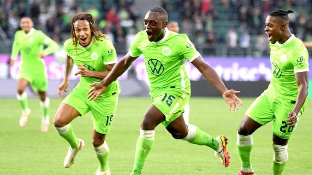 Wolfsburgs Jerome Roussillon (M) jubelt nach seinem Treffer zum 1:0 mit seinen Teamkollegen Kevin Mbabu (l) und Ridle Baku (r). Wolfsburgs Jerome Roussillon (M) jubelt nach seinem Treffer zum 1:0 mit seinen Teamkollegen Kevin Mbabu (l) und Ridle Baku (r).