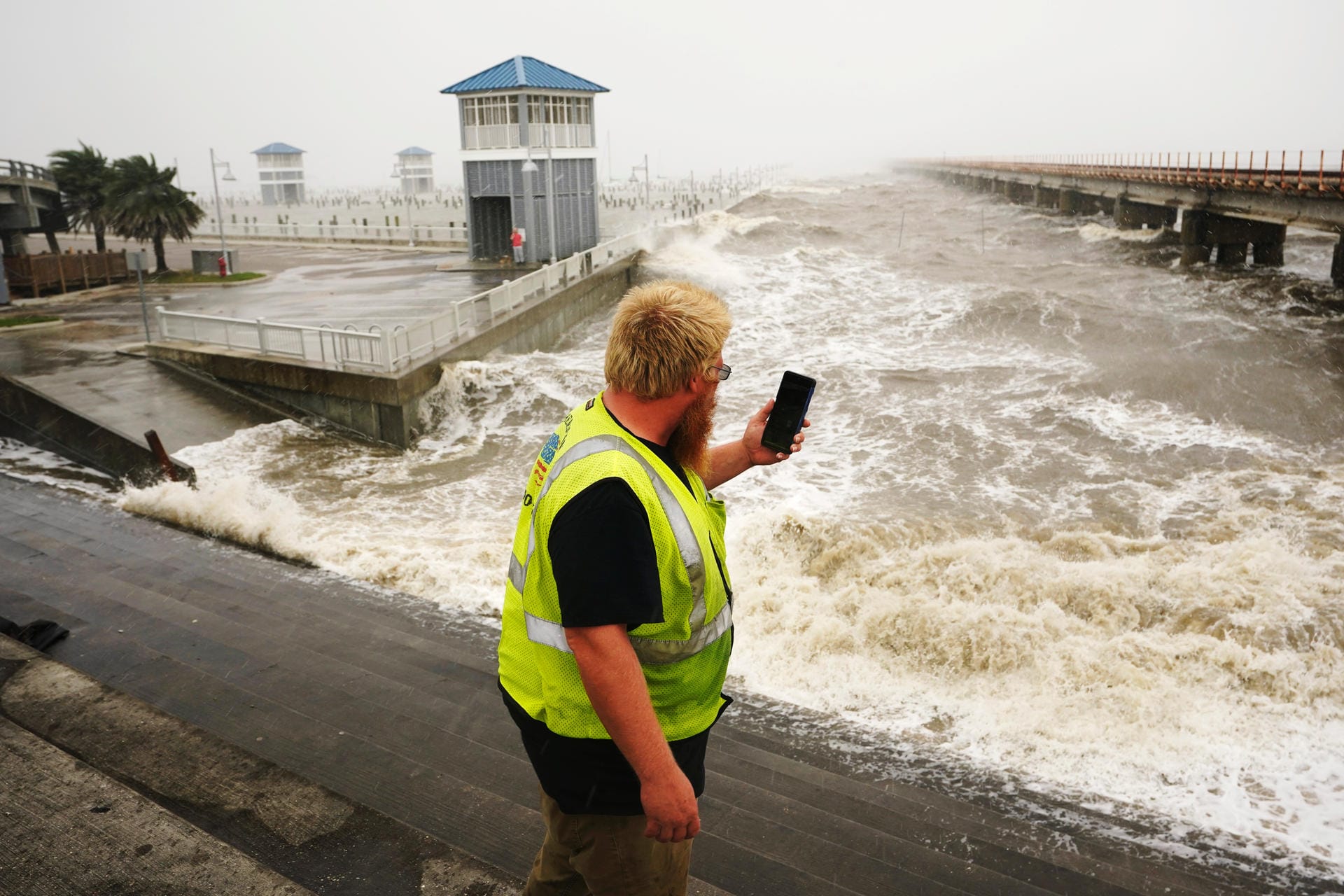 Ein Arbeiter filmt die hohen Wellen an der Küste von Louisiana.