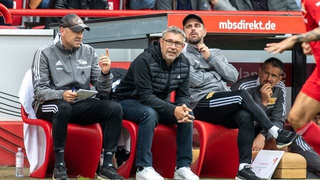 Unions Co-Trainer Markus Hoffmann, Trainer Urs Fischer und Co-Trainer Sebastian Bönig (l-r) sitzen auf Bank. Unions Co-Trainer Markus Hoffmann, Trainer Urs Fischer und Co-Trainer Sebastian Bönig (l-r) sitzen auf Bank.