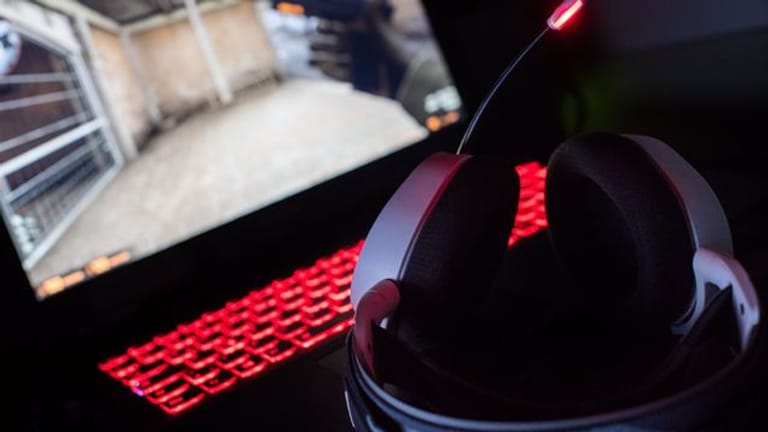 Ein Gaming-Kopfhörer liegt auf einem Gaming-Laptop auf einem Tisch.