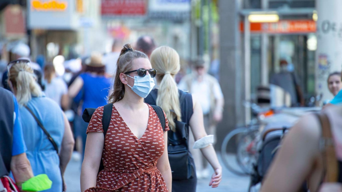 Eine Frau mit Mund-Nasen-Schutz läuft durch eine Fußgängerzone (Symbolbild): Die Inzidenz in Deutschland ist leicht gesunken.