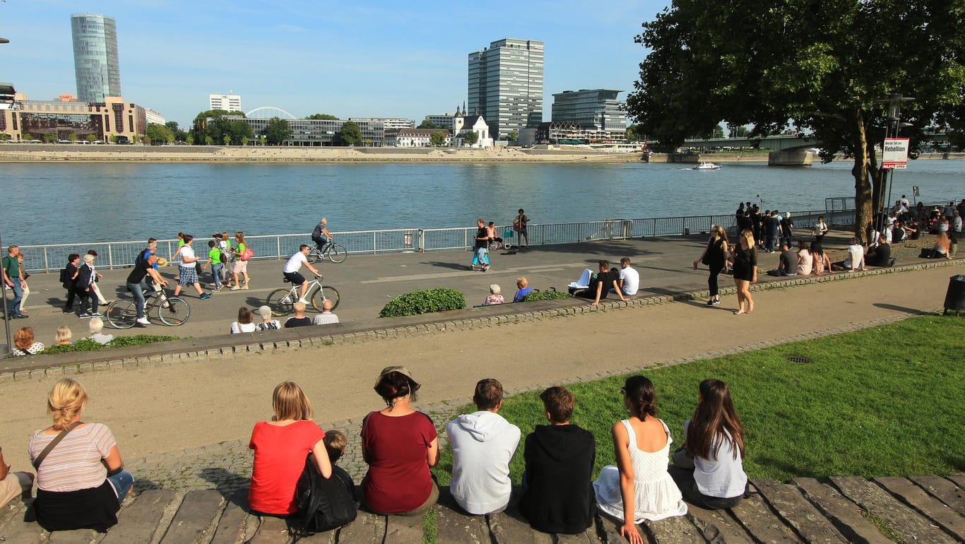Menschen genießen die Sonne am Rheinufer in Köln: Hier werden es noch einmal bis zu 26 Grad (Symbolbild).