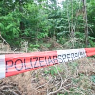 Absperrband der Polizei in einem Wald (Symbolbild): Die Frau lag nach Angaben der Polizei an einem schwer zugänglichen Ort.