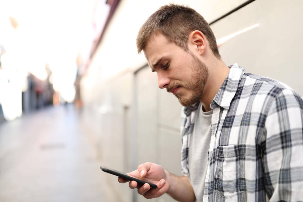 Ein Mann schaut auf sein Smartphone (Symbolbild): Vorsicht vor Betrugs-SMS.