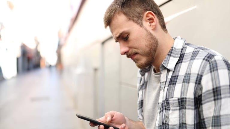 Ein Mann schaut auf sein Smartphone (Symbolbild): Vorsicht vor Betrugs-SMS.