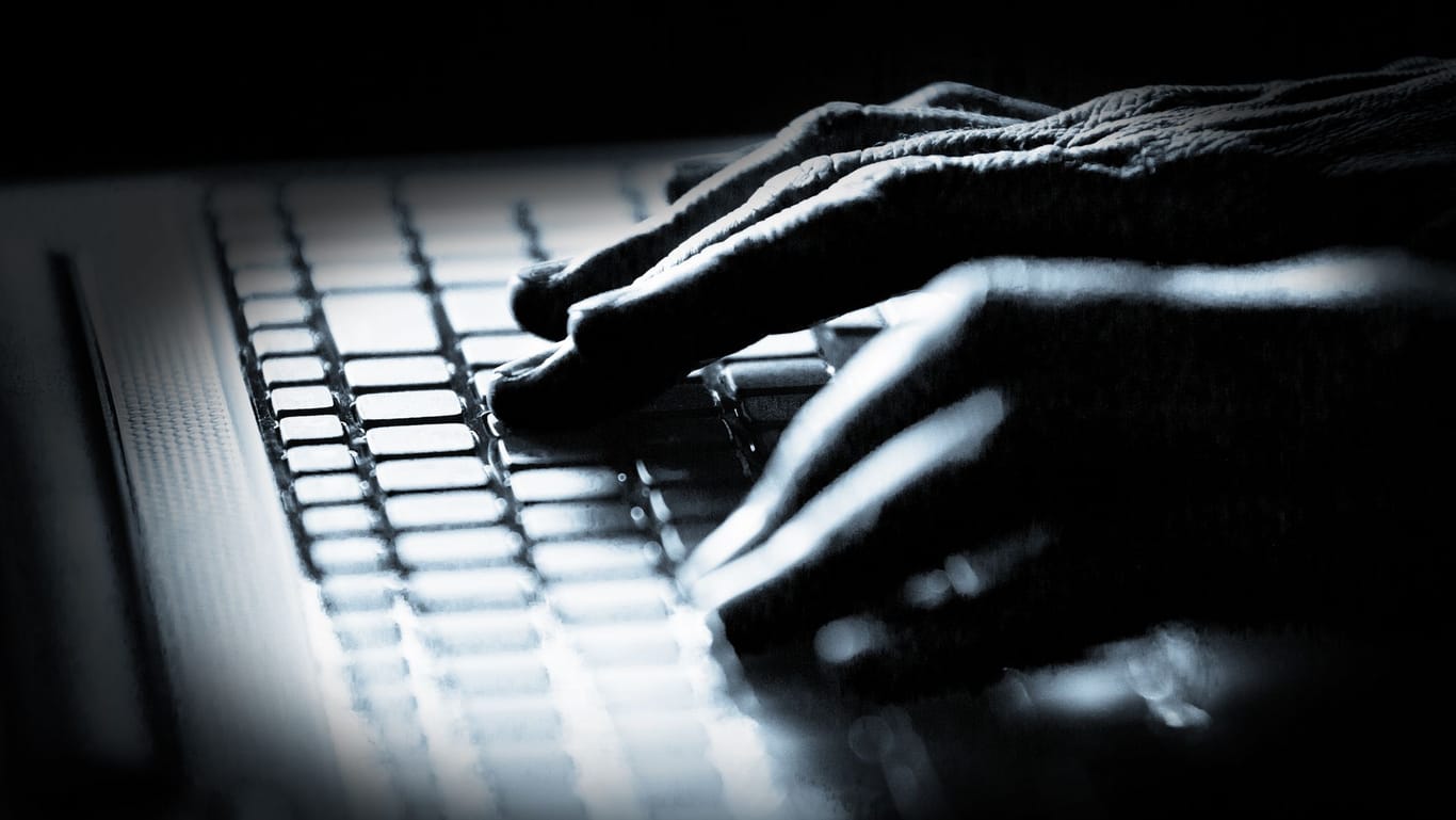 Ein Mann an einem Rechner (Symbolbild): Cyberattacken können für Unternehmen teuer werden.