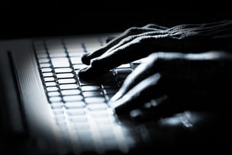 Ein Mann an einem Rechner (Symbolbild): Cyberattacken können für Unternehmen teuer werden.