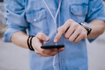 Ein Mann am Smartphone: Servicenummern sollen für Handynutzer günstiger werden.