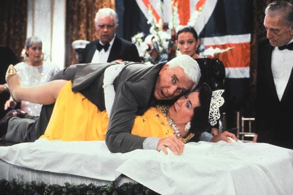 Leslie Nielsen in seiner bekanntesten Rolle als Lt. Frank Drebin in "Die nackte Kanone" (USA 1988) mit Jeanette Charles als Queen. Am 28. November 2010 starb er mit 84 Jahren an einer Lungenentzündung. ( Leslie Nielsen in seiner bekanntesten Rolle als Lt. Frank Drebin in "Die nackte Kanone" (USA 1988) mit Jeanette Charles als Queen. Am 28. November 2010 starb er mit 84 Jahren an einer Lungenentzündung. (