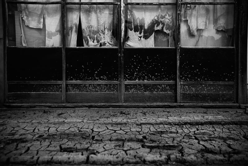 Der Gehweg von getrocknetem Schlamm verkrustet, die Schaufenster leer. Der Gehweg von getrocknetem Schlamm verkrustet, die Schaufenster leer.